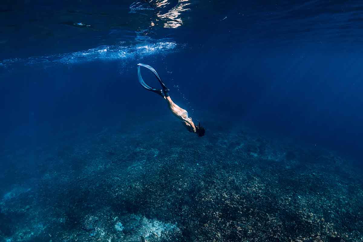 graceful female freediver diving into the reefs